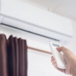 A man use remote controller to set air conditioner temperature in the room.Hand holdind control remote switch of home air conditioner